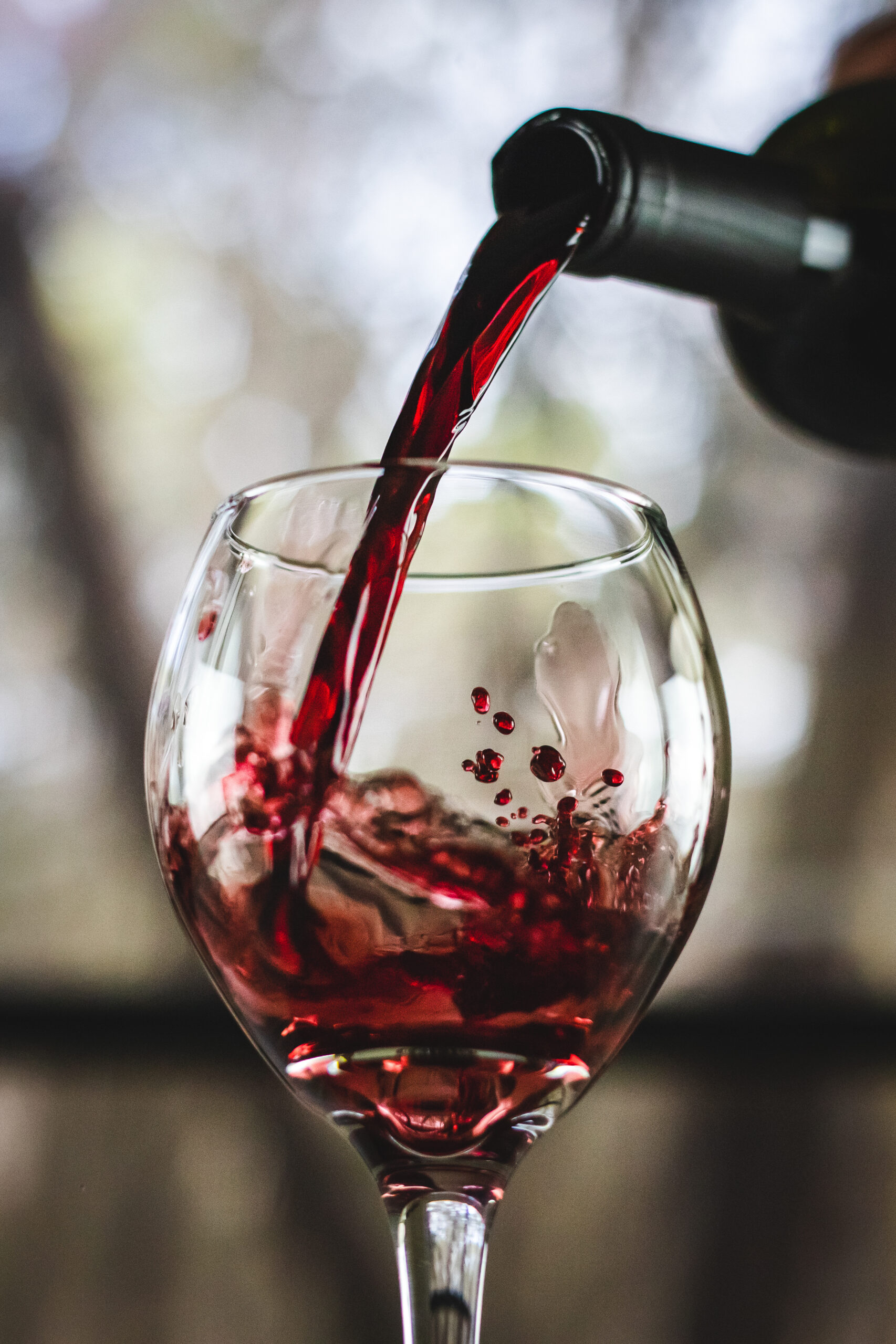 A closeup shot of red wine pouring in glass isolated on blurry background